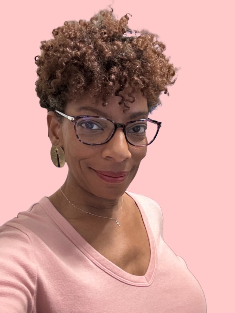 Photo of Black woman with short curly hair dressed in pink.