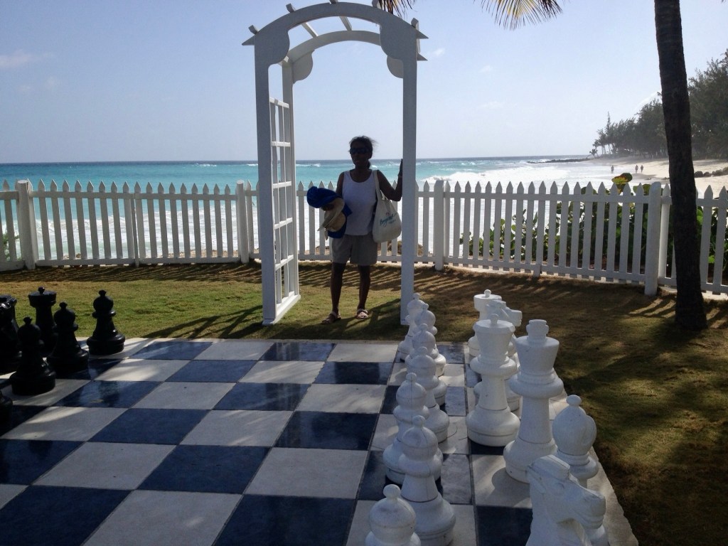 My mother, Carolyn, standing at a giant chess board on a Barbados beach.